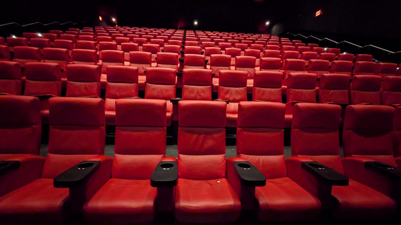 Empty red cinema seats in a darkened auditorium